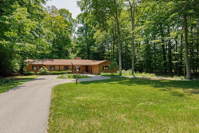 ranch-style home with a garage, driveway, a chimney, and a front yard