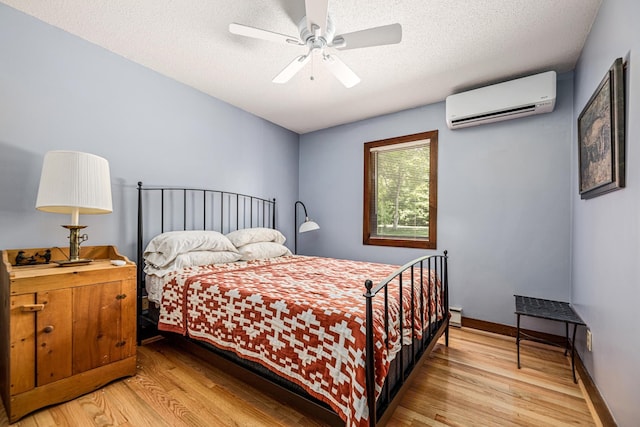 bedroom with wood finished floors, a textured ceiling, and a wall unit AC