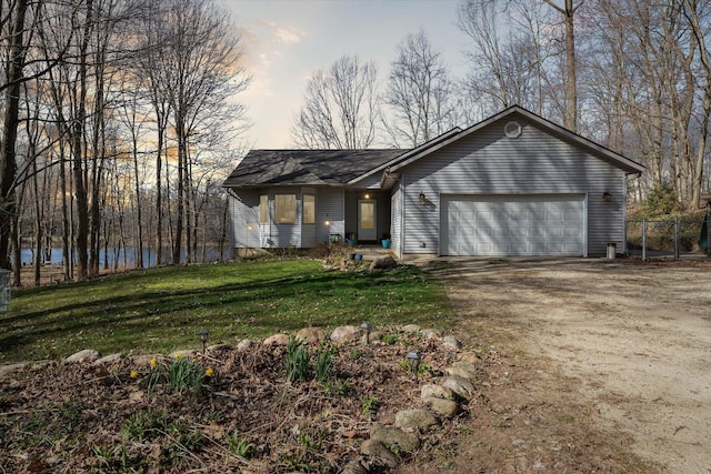 single story home featuring a water view, fence, a front lawn, a garage, and driveway