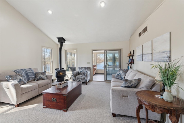 living area featuring light carpet, a wood stove, visible vents, and a wealth of natural light