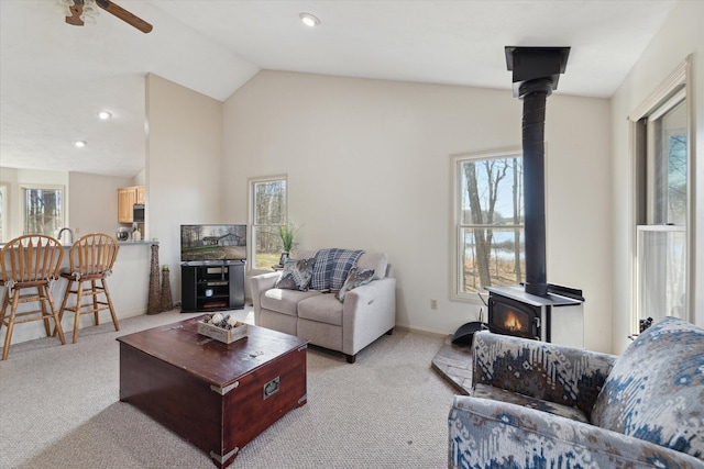 living area featuring a wood stove, light carpet, and a healthy amount of sunlight