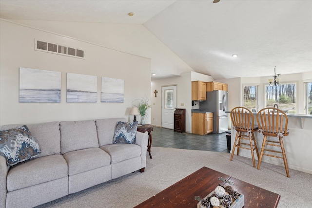 living area with dark carpet, visible vents, a notable chandelier, and vaulted ceiling