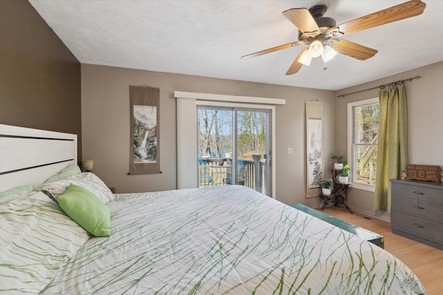 bedroom featuring access to outside, light wood finished floors, ceiling fan, and multiple windows