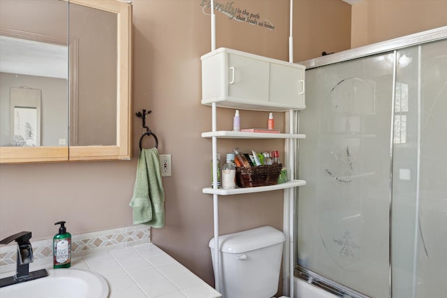 bathroom with toilet, a sink, and a shower with door