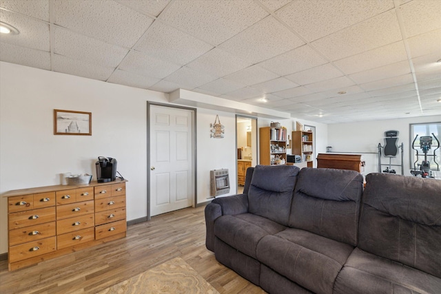 living area with light wood-style floors, a drop ceiling, and heating unit