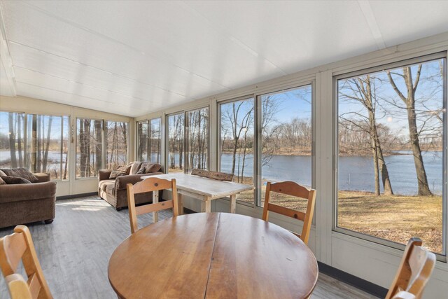 sunroom / solarium featuring a water view, wood finished floors, and vaulted ceiling