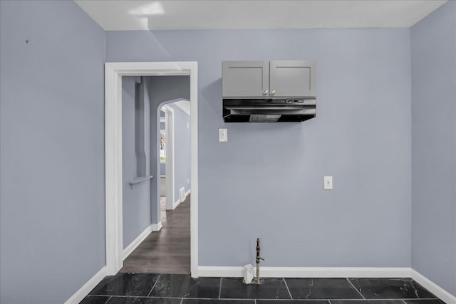 kitchen featuring arched walkways, baseboards, and under cabinet range hood