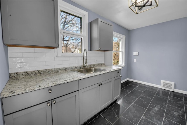 kitchen featuring baseboards, gray cabinets, and a sink