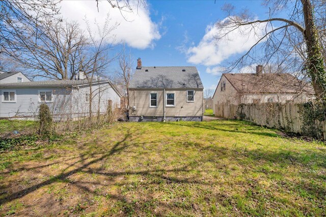 back of house featuring fence, a chimney, and a yard