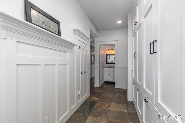 hall featuring recessed lighting, a sink, and stone tile flooring