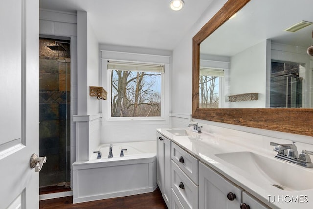full bath with tiled shower, a sink, a garden tub, and visible vents