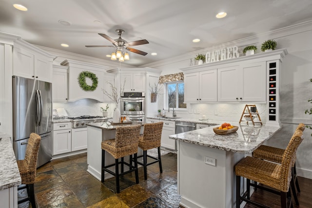 kitchen featuring a peninsula, white cabinetry, a ceiling fan, a breakfast bar area, and stainless steel appliances