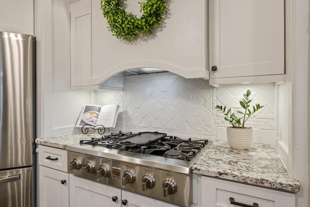 kitchen featuring tasteful backsplash, white cabinets, and appliances with stainless steel finishes