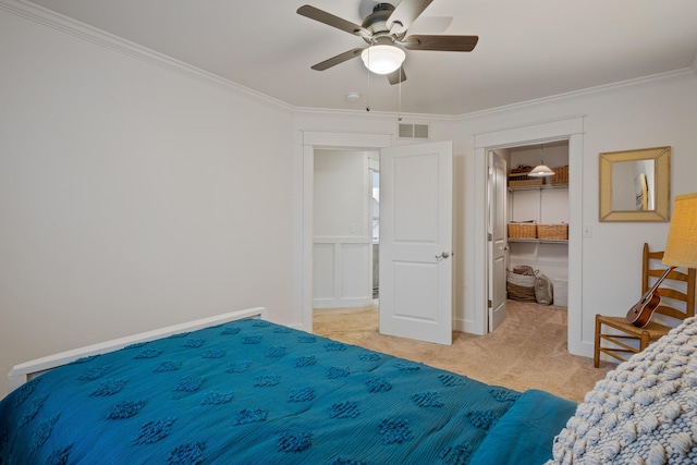 bedroom featuring light carpet, a spacious closet, ornamental molding, and visible vents