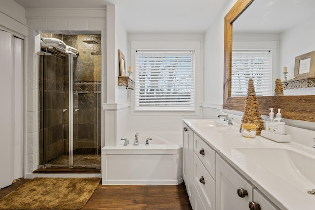 full bathroom featuring a bath, a stall shower, wood finished floors, and a sink