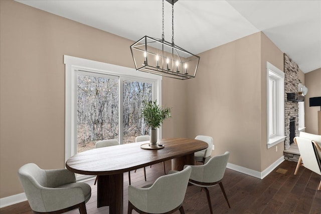 4070 Metamora Rdg, Metamora, MI 48455 - dining room featuring a chandelier, dark wood-style flooring, baseboards, and a stone fireplace