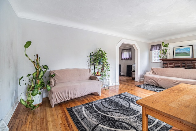living room featuring arched walkways, baseboards, and wood finished floors