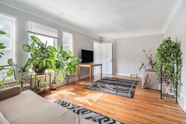 living room with plenty of natural light, wood finished floors, and ornamental molding