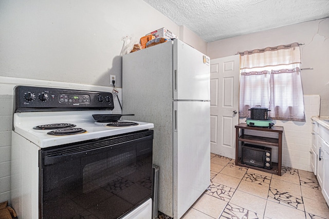 kitchen featuring electric range, a textured ceiling, freestanding refrigerator, and light countertops