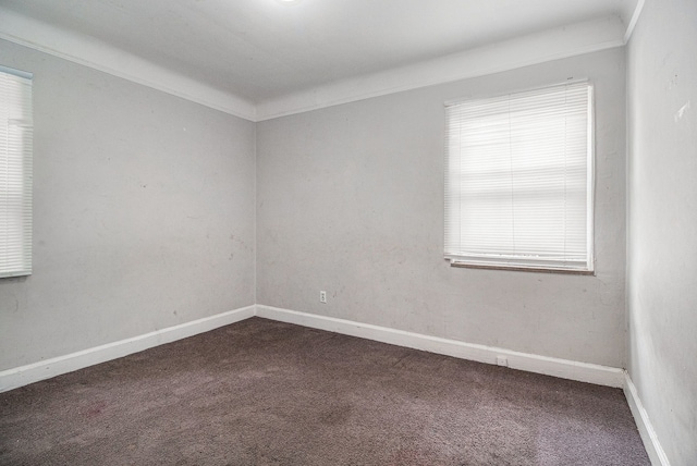 spare room featuring dark colored carpet and baseboards
