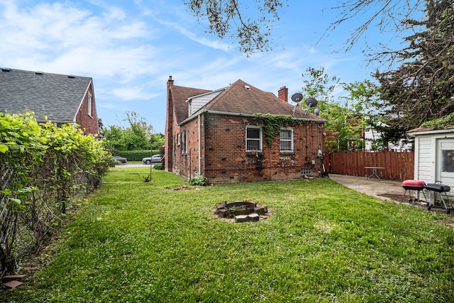 back of property with a chimney, a fire pit, brick siding, and a patio