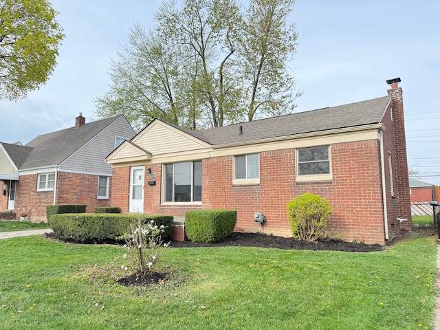 single story home featuring a chimney, brick siding, and a front yard