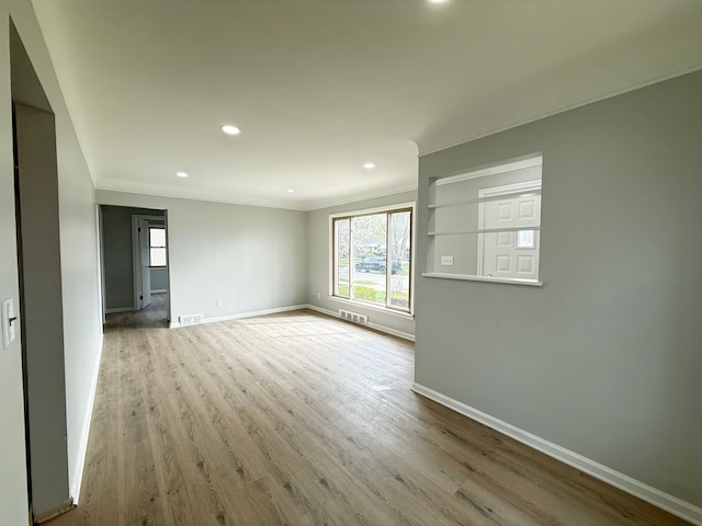 spare room featuring recessed lighting, visible vents, baseboards, ornamental molding, and wood finished floors