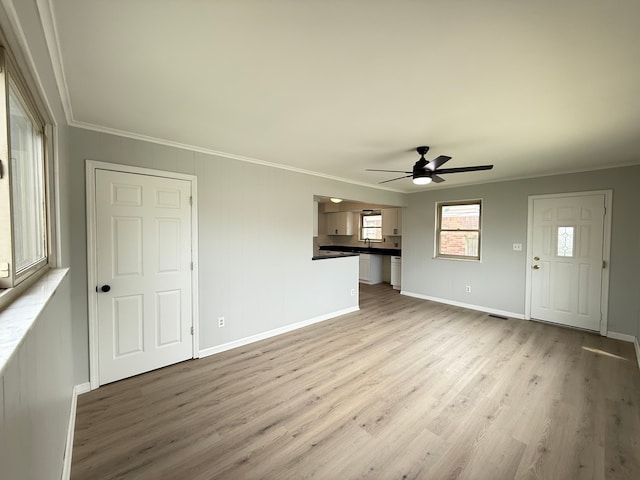 unfurnished living room featuring crown molding, a ceiling fan, baseboards, and light wood-style floors