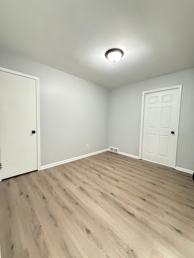 unfurnished room featuring baseboards, visible vents, and light wood-style flooring