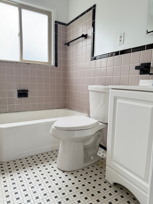 bathroom with tile patterned flooring, tile walls, toilet, a bathtub, and vanity