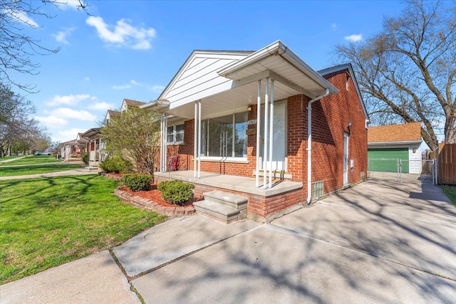 view of front of house with a gate, a front lawn, driveway, covered porch, and brick siding