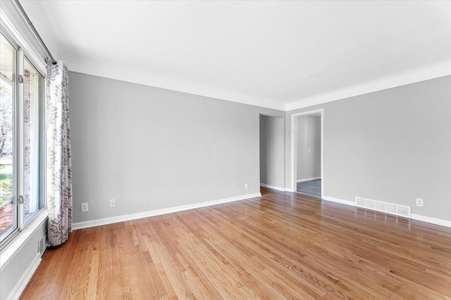 unfurnished room featuring light wood-style floors, visible vents, and baseboards