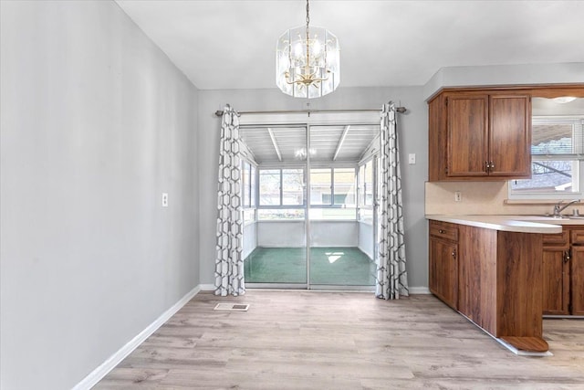 unfurnished dining area featuring baseboards, a notable chandelier, visible vents, and light wood-type flooring