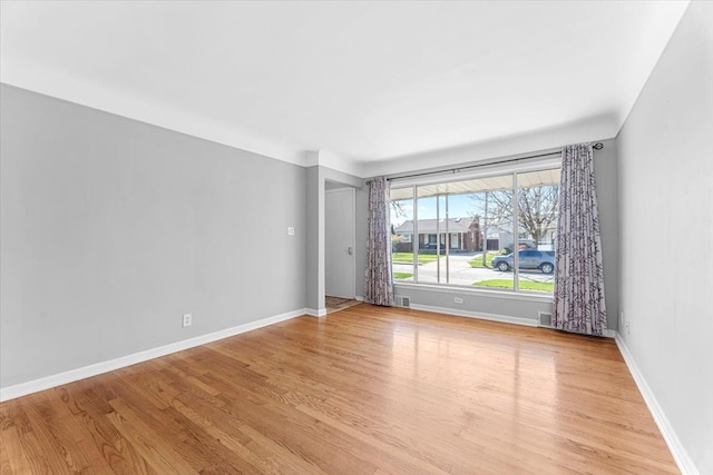 spare room featuring baseboards, visible vents, and light wood finished floors