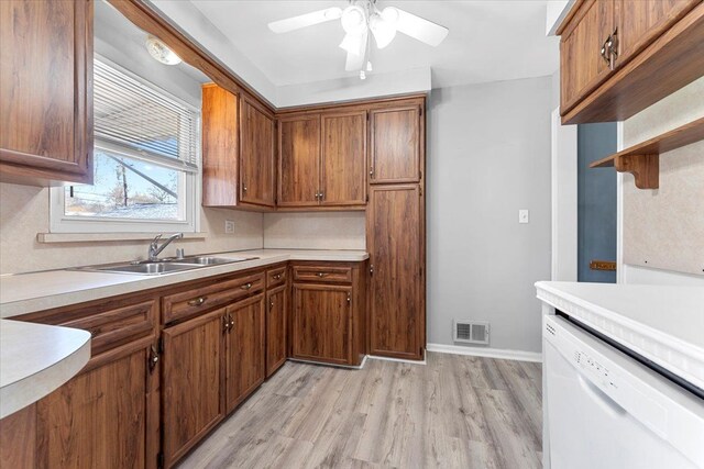 kitchen featuring brown cabinets, light countertops, dishwasher, visible vents, and a sink