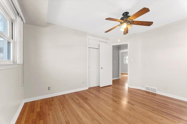 unfurnished room featuring ceiling fan, a wealth of natural light, light wood finished floors, and visible vents