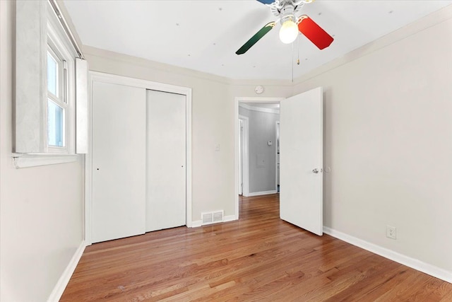 unfurnished bedroom featuring a closet, light wood-type flooring, ceiling fan, baseboards, and visible vents