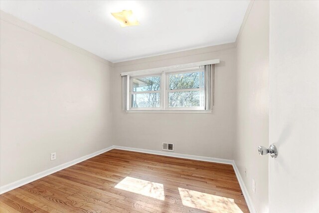 unfurnished room featuring wood finished floors, crown molding, and baseboards