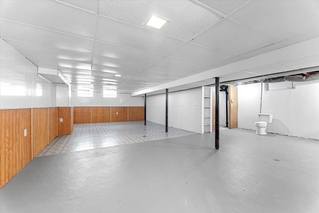basement with wooden walls and a drop ceiling