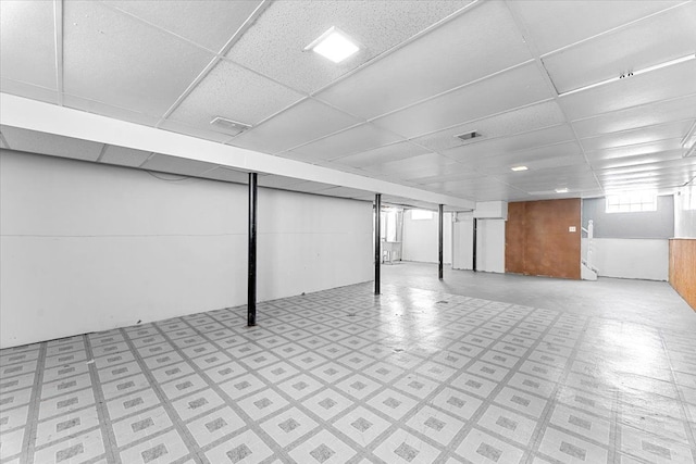 basement with tile patterned floors, visible vents, and a drop ceiling