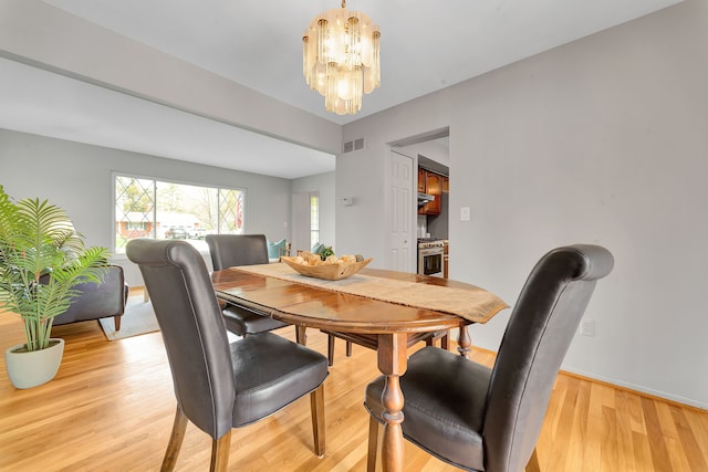 dining area featuring visible vents, baseboards, a chandelier, and light wood finished floors