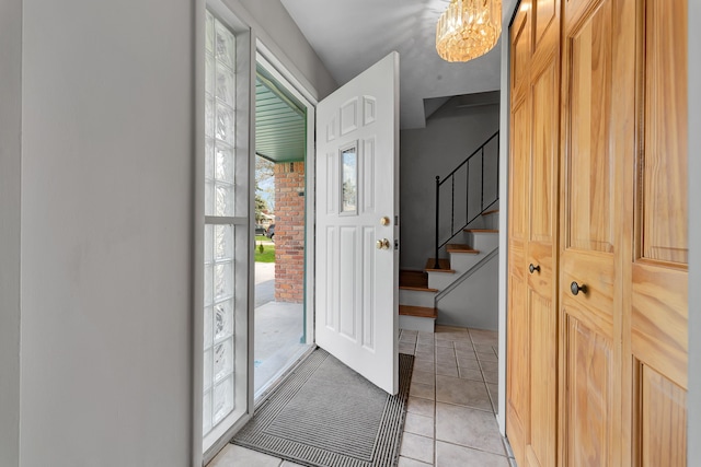 entrance foyer featuring stairway, light tile patterned floors, and an inviting chandelier