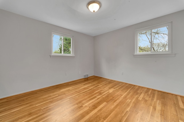 spare room with light wood-style floors, baseboards, and visible vents