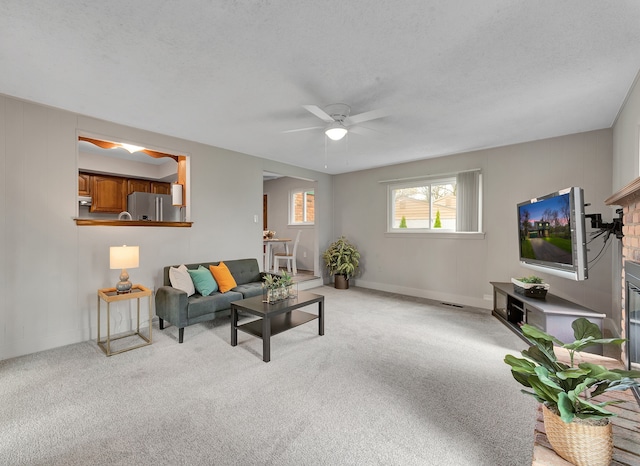 living area with baseboards, visible vents, a ceiling fan, and light colored carpet