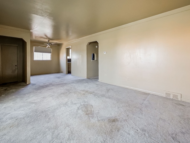 unfurnished room with ceiling fan, light carpet, arched walkways, and baseboards