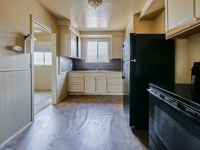 kitchen with a sink, concrete flooring, range, backsplash, and freestanding refrigerator