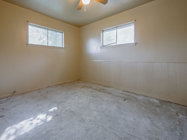 unfurnished room with wainscoting, ceiling fan, and carpet