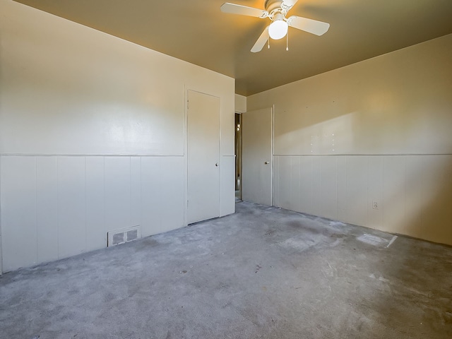 empty room featuring a wainscoted wall and ceiling fan