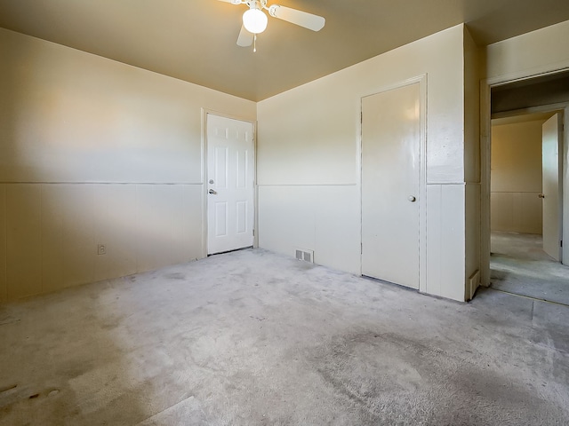 unfurnished bedroom featuring carpet flooring, a wainscoted wall, and ceiling fan