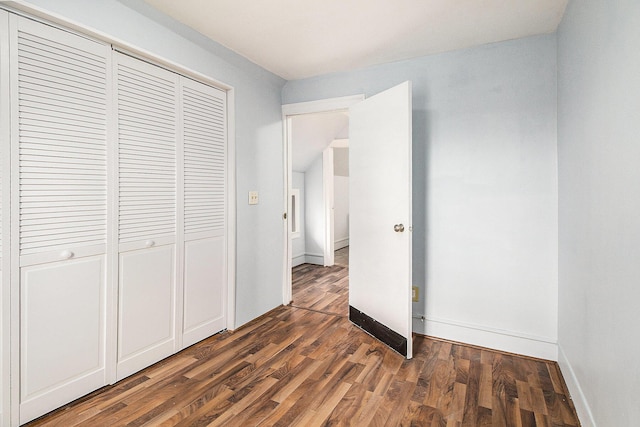 unfurnished bedroom featuring a closet, wood finished floors, and baseboards